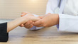© EduLife Photos - Close up and crop shoot of young Asian female doctor holds an adult female patient’s hand to examine and diagnose her sickness and symptom. Medicine and health care concept. Doctor and patient.