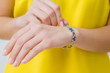 Young woman in yellow, bright clothes wearing blue flower bracelet on her hand wrist. Daily beauty. Front view. Closeup.