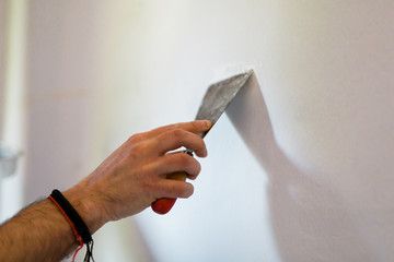 Doing homework. Adult man repairing holes on a wall with putty