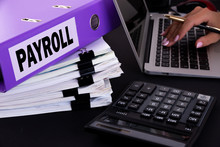 Text, Word Payroll Is Written On A Folder Lying On Documents On An Office Desk With A Laptop And A Calculator. Business Concept.