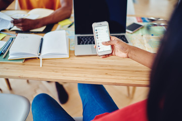 Wall Mural - Crop freelancer using smartphone during work at home