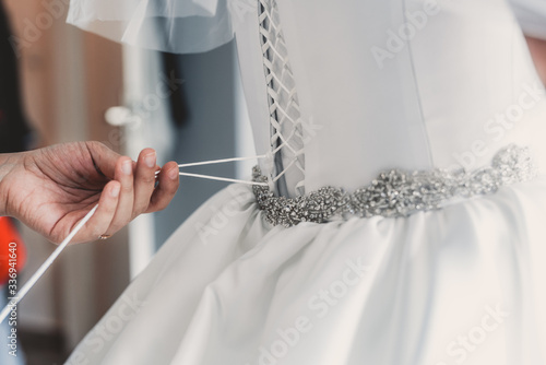 Fotomural Hochzeitskleid wird an der Braut zugeschnürrt