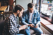 © BullRun - Adult males friends browsing smartphones in cafe