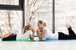 © FreepikCompany - Side view of mother and daughter posing on yoga mat
