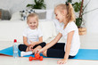 © FreepikCompany - Happy girls exercising at home on yoga mat with weights