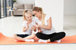 © FreepikCompany - Front view of mother and daughter at home on yoga mat playing on smartphone