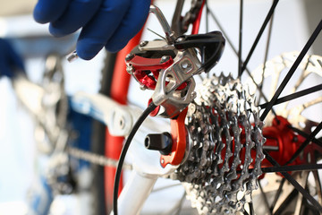 Wall Mural - Close-up of mechanic serviceman installing assembling or adjusting bicycle gear on wheel in workshop. Technical expertise. Bike maintenance and repair service concept