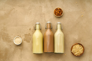 Wall Mural - Dairy alternative. Rice, oat and chocolate almond milk in glass bottles on beige background. Healthy protein vegan drink. View from above