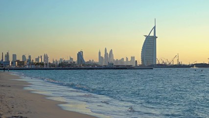 Wall Mural - Burj Al Arab in Jumeirah Island or boat building with waves on sea beach, Dubai Downtown skyline, United Arab Emirates or UAE. Financial district in urban city. Skyscrapers at sunset.