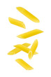 Falling penne pasta. Flying yellow raw macaroni over white background.