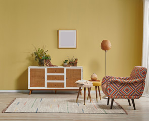 Wall Mural - Yellow living room wall and wicker cabinet, orange lamp and frame style with chair.
