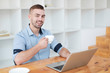 © Somkiat - Young man drinking coffee while working with laptop. Hand man drinking coffee in office while typing on laptop in a cafe