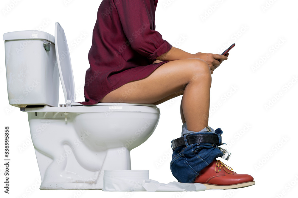 Man wearing jeans and shoes using phone while sitting on a toilet isolate on white background