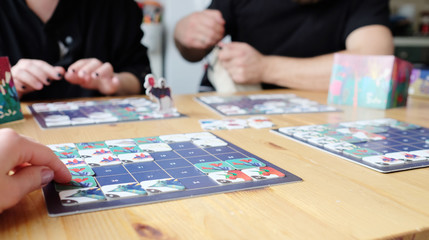 Only hends visible. Friends sitting playing board game at wooden table. Concept spending time at home. Selective focus