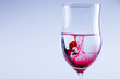 © andsko - Red liquid splash in water. Wine glass isolated.