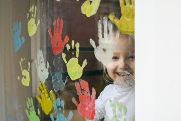 Girl paints with palms on the window. Quarantine