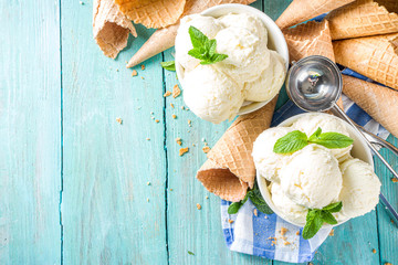 Wall Mural - Homemade white vanilla ice cream balls with mint leaves in small portioned white bowl. With ice cream waffle cone and spoon,  on rustic turquoise wooden table, copy space