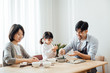© JodieWang - Mom and Dad and daughter at home dumplings
