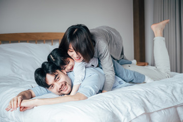 Wall Mural - Mom and Dad and daughter in the bedroom playing games