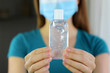 © zigres - COVID-19 Pandemic Coronavirus Close up Woman Mask Hand Showing Alcohol Gel Sanitizer Dispenser Against 2019-nCoV. Antiseptic, Hygiene and Healthcare concept. Focus on hand and gel dispenser.