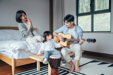 Wall Mural - Mom and Dad and daughter sing at home