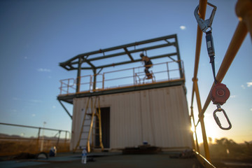 Wall Mural - Safe work practices defocused an inertia reel shock absorbing fall protection hook lanyard device clipping hanging on handrail construction worker working in fall arrest fall restraint background