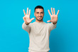 © luismolinero - Young man over isolated blue background counting nine with fingers