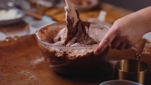 Mixing Cocoa Flour Chocolate Cake Batter In A Glass Bowl With A Wooden Spoon And Remove From Frame. Static Shot. Close Up.
