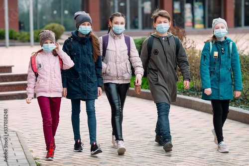 Cuadros en Lienzo Children students in medical masks leave the school.