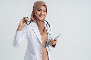 Wall Mural - female doctor hijab using stethoscope and smile to camera over white background