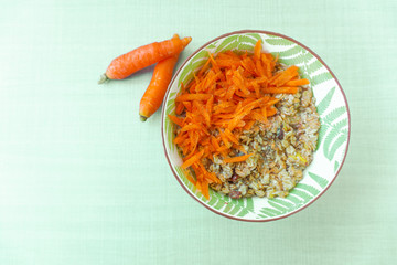 Wheat homemade porridge with oats sunseeds raisen and slised of carrots and cinnamon topings in a cute bowl on a wooden table - Healthy meals and dieting lifestyle in a easter theme dish