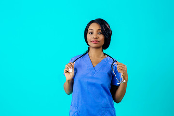 Portrait of a young female doctor in blue scrubs uniform holding stethoscope, isolated on blue background