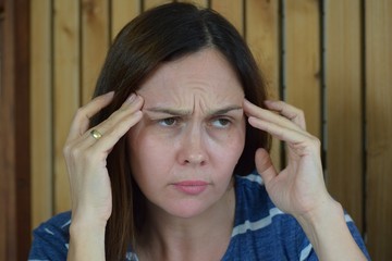 A woman in a striped dress with a headache.A woman in a striped dress holds her head.