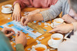 Close-up of family of four sitting at the table drinking tea and collecting puzzles together
