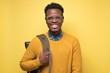 © Viktor Koldunov - Happy african american college student holding backpack and smiling being glad to study. Studio shot on yellow wall.