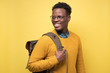 © Viktor Koldunov - Happy african american college student holding backpack and smiling being glad to study. Studio shot on yellow wall.