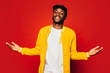 © MyMicrostock/Stocksy - Happy young black man looking at camera over a red background