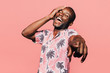 © MyMicrostock/Stocksy - Happy young black man laughing at pointing at camera with finger over pink background