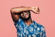 © MyMicrostock/Stocksy - Portrait of black man covering his face with arm over light pink background