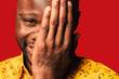 © MyMicrostock/Stocksy - Happy young black man smiling at camera with hand on face