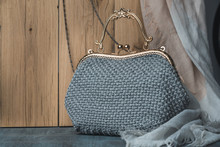Gray Knitted Bag. Handmade Crochet Purse. Close-up Of Monochrome Handbag On The Oak Wood Background. Strong Texture. Free Copy Space. Place For Advertisement. Product Photo.