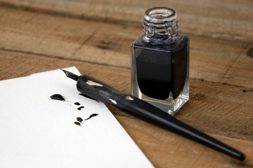 Ink and artists pen with white art paper, ink spill, wooden background