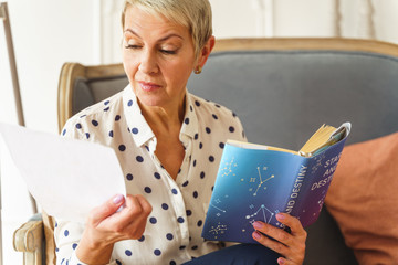 Wall Mural - Pleasant blonde woman holding an astrology book