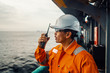 © Igor Kardasov - Filipino deck Officer on deck of vessel or ship , wearing PPE personal protective equipment. He speaks to VHF walkie-talkie radio in hands. Dream work at sea