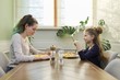 © Valerii Honcharuk - Children two girls eat lunch sitting at table in home kitchen, homemade food
