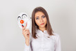 © hbrh - Doubtful inside. Wearing a mask. Portrait young doubtful worried woman with skeptical expression holding a clown mask expressing cheerfulness happiness looking at camera isolated white background.