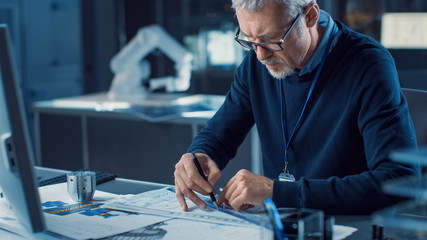 Fototapete - Professional Heavy Industry Engineer Draws Engine Concept Blueprint, References Computer. Engineering Bureau and Industrial Design Laboratory with Various Components in Sight