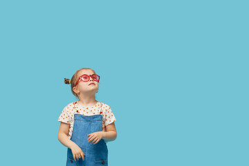 Portrait of surprised cute little toddler girl child standing isolated over blue background. Holding a gift box. Empty space for text