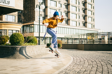 Skateboarding at city. Female, enjoyment. Hipster girl riding skate board. Ride, style. Extreme sport and emotions concept. Alternative lifestyle. Woman skateboarder skateboarding at city