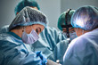 © Georgii - In the hospital operating room. An international team of professional surgeons and assistants works in a modern operating room. Professional doctors celebrate successfully saved lives.